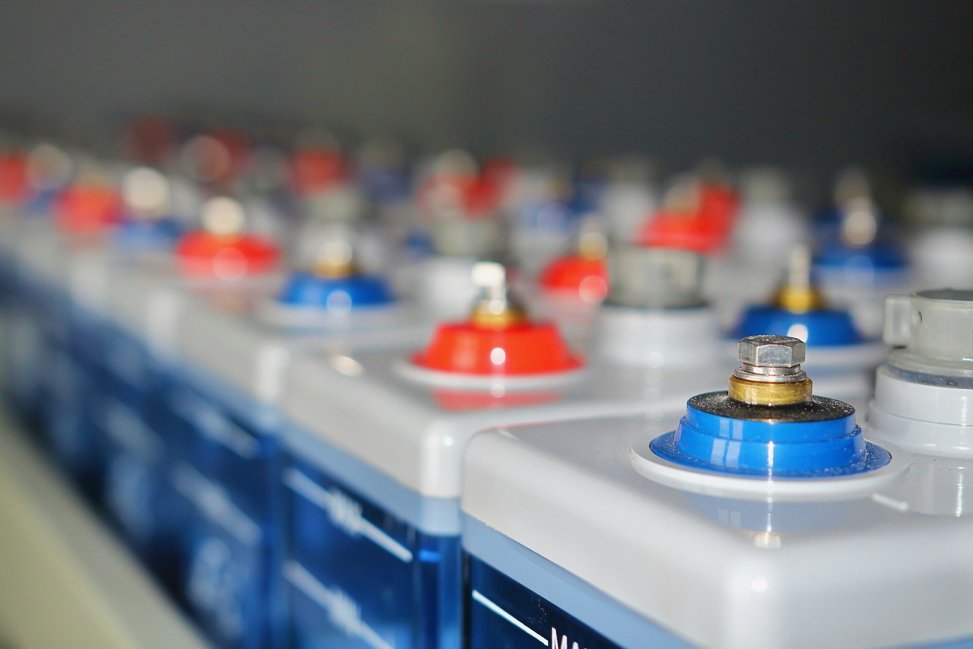 Row of stationary battery cells with red and blue terminal posts