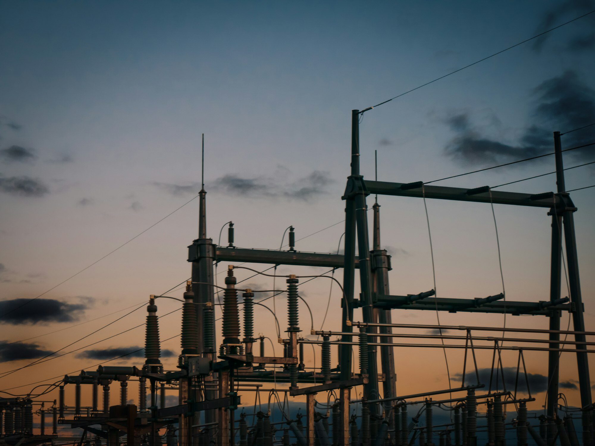 Substation structures and insulators silhouetted at dusk